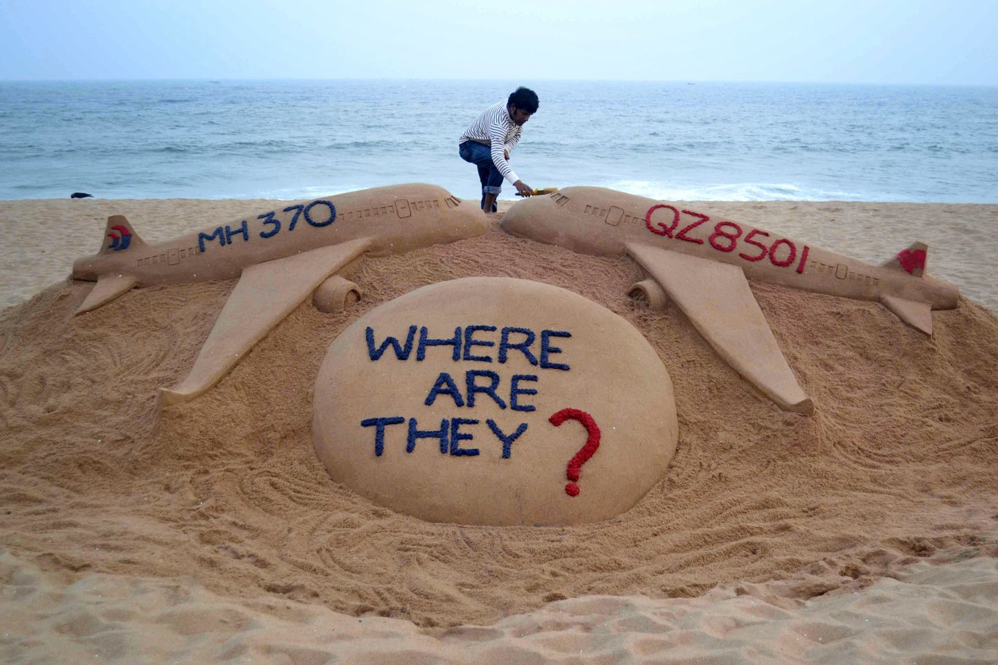 Liivaskulptuur, mis küsib, kus on lend MH370 ja praeguseks leitud AirAsia lend QZ8501.