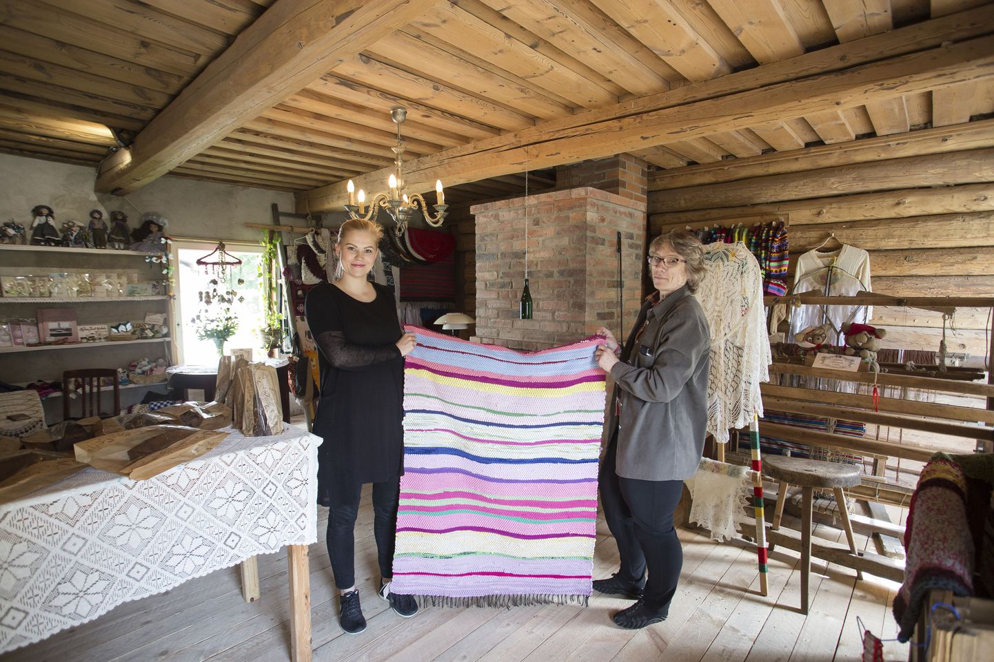 Helena Mägi (vasakul) ja Krista Kalm näitavad ühte paljudest triibulistest vaipadest, mida võimalik nende poest osta.