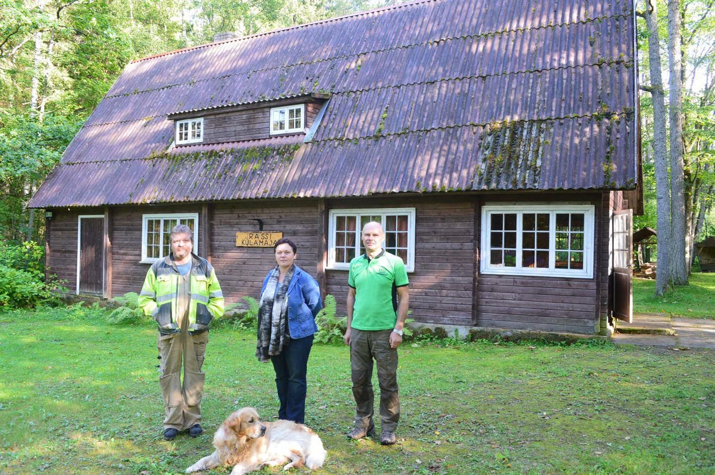 Rassi rahva kogunemiskoha, külamaja ees seisavad külaseltsi asutajaliikmed Aleksander Leppik (vasakult), Kirsti Eesmäe ja Elor Ilmet, neid valvab Ilmeti koer Ronni.