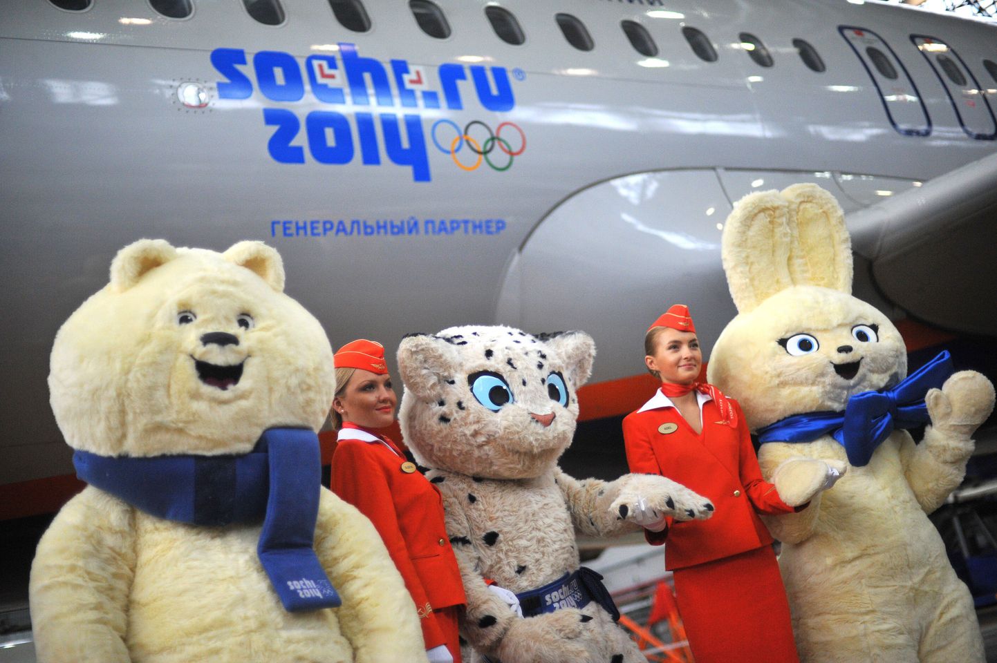 Sotši olümpia maskotid poseerimas olümpialogo kandva lennuki ees.