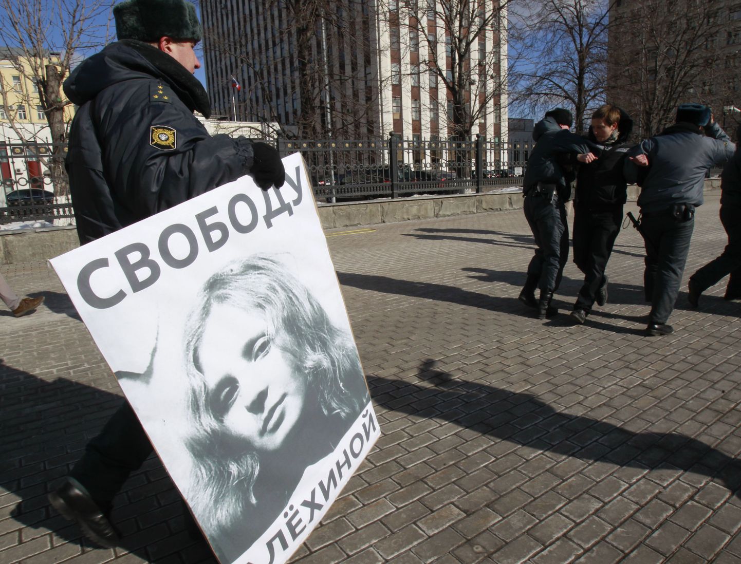Vene politseinik tassib plakatit, millega nõutakse Pussy Rioti liikme Maria Aljohhina vabastamist.