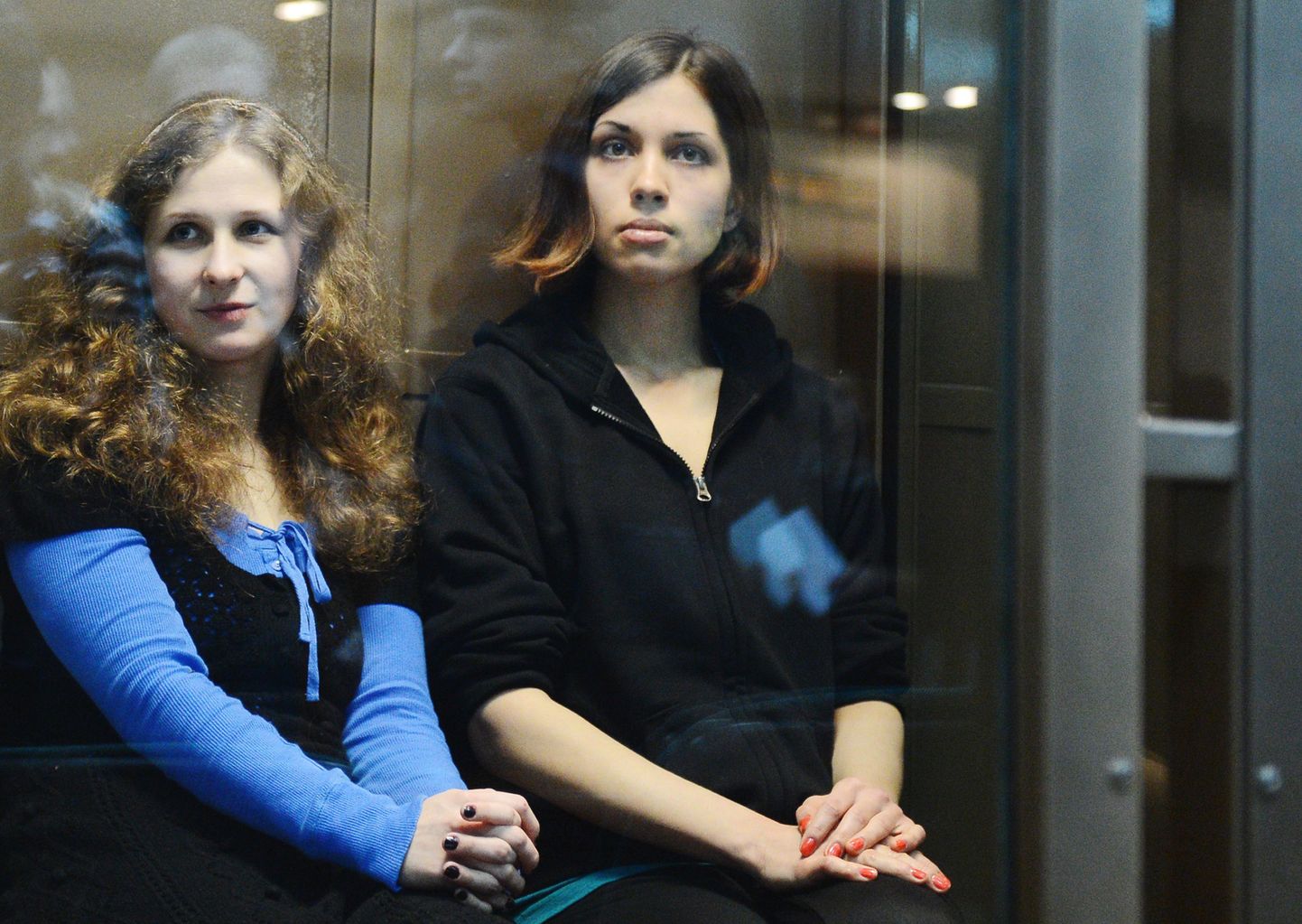 (FILES) A file picture taken on October 10, 2012, shows two jailed members of the all-girl punk band "Pussy Riot," (L-R) Maria Alyokhina and Nadezhda Tolokonnikova, sitting in a glass-walled cage in a court in Moscow. Maria Alyokhina, one of the jailed members of Russian punk band Pussy Riot, was freed from prison on December 23, 2013 after receiving amnesty, her lawyer and prison officials said. "Today around 9 a.m. (0500 GMT) she walked out to freedom," said the spokeswoman of the prison service in Nizhny Novgorod Yelena Nikishova.
. AFP PHOTO / NATALIA KOLESNIKOVA