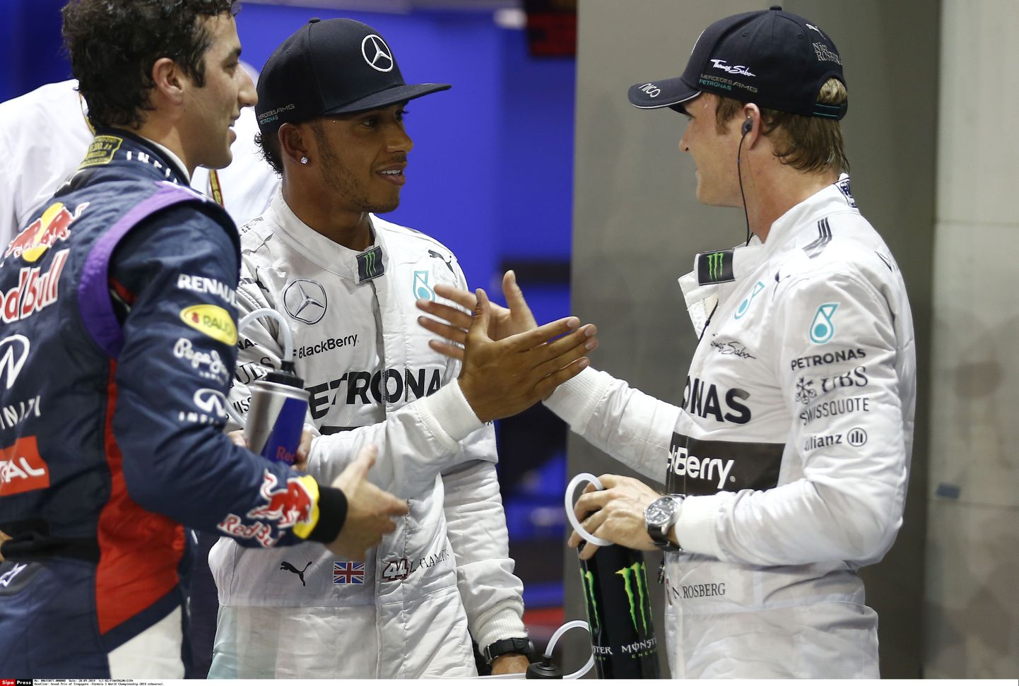 Lewis Hamilton (keskel) ja Nico Rosberg (paremal) üksteisel kätt surumas.