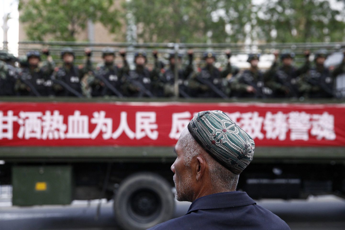 Uiguuri mees vaatamas mööduvat veokitäit Hiina politsei eriüksuslasi.