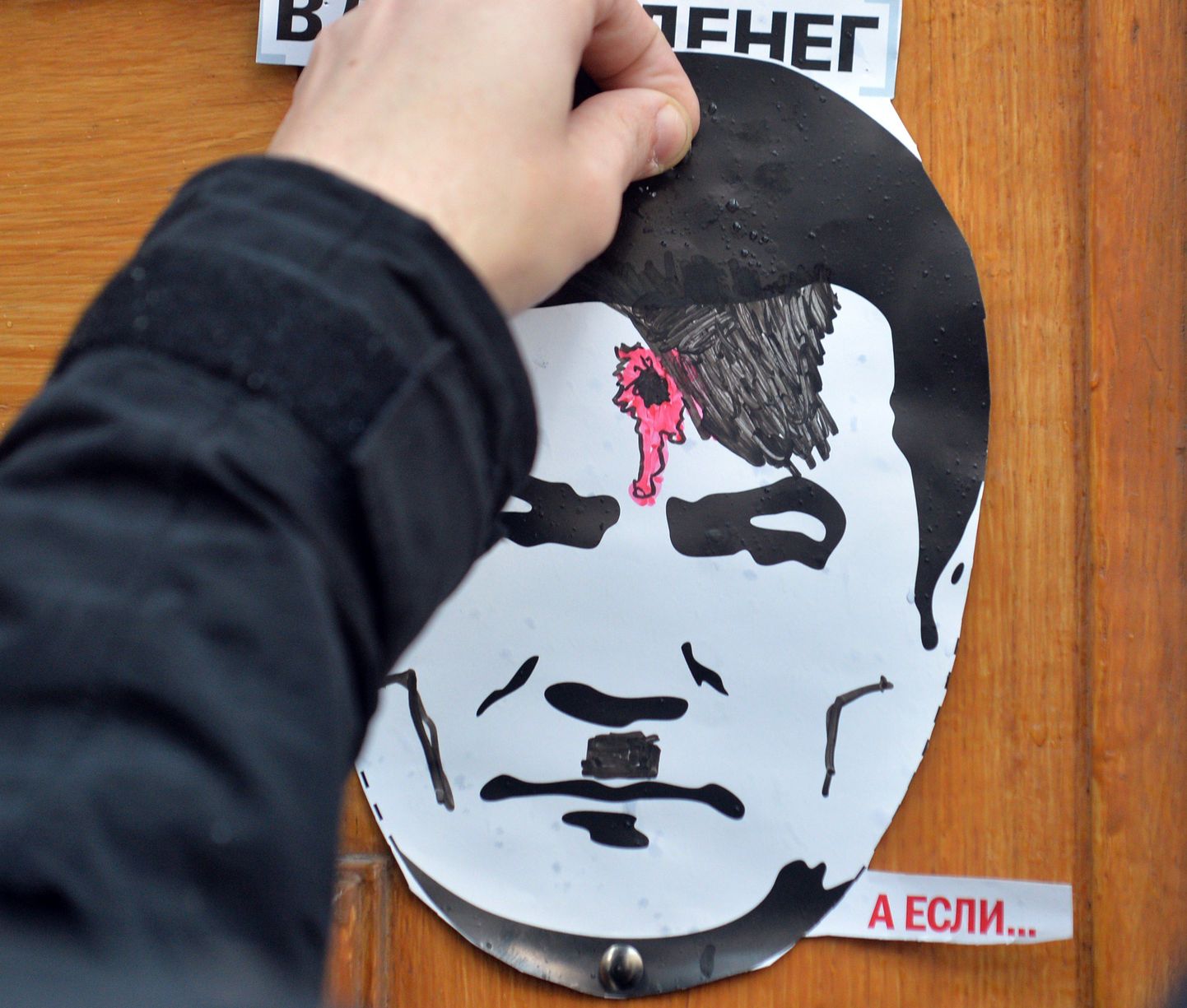 Mees kinnitab plakatit, millel on Ukraina presidenti Viktor Janukovõtšit kujutatud Adolf Hitlerina, kellel on kuulihaav peas.