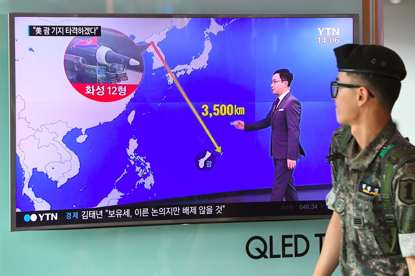 Lõuna-Korea sõdur möödumas teleekraanist, kus näidatakse vahemaad Põhja-Korea ja Guami vahel.