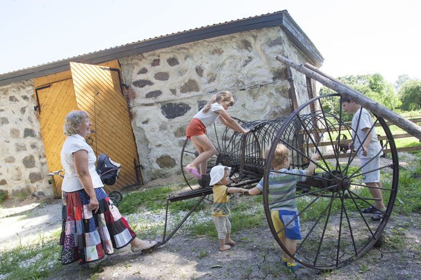 Margot Mitt näitab Emumäe küla lastele muuseumi ees seisvat vana looreha.
