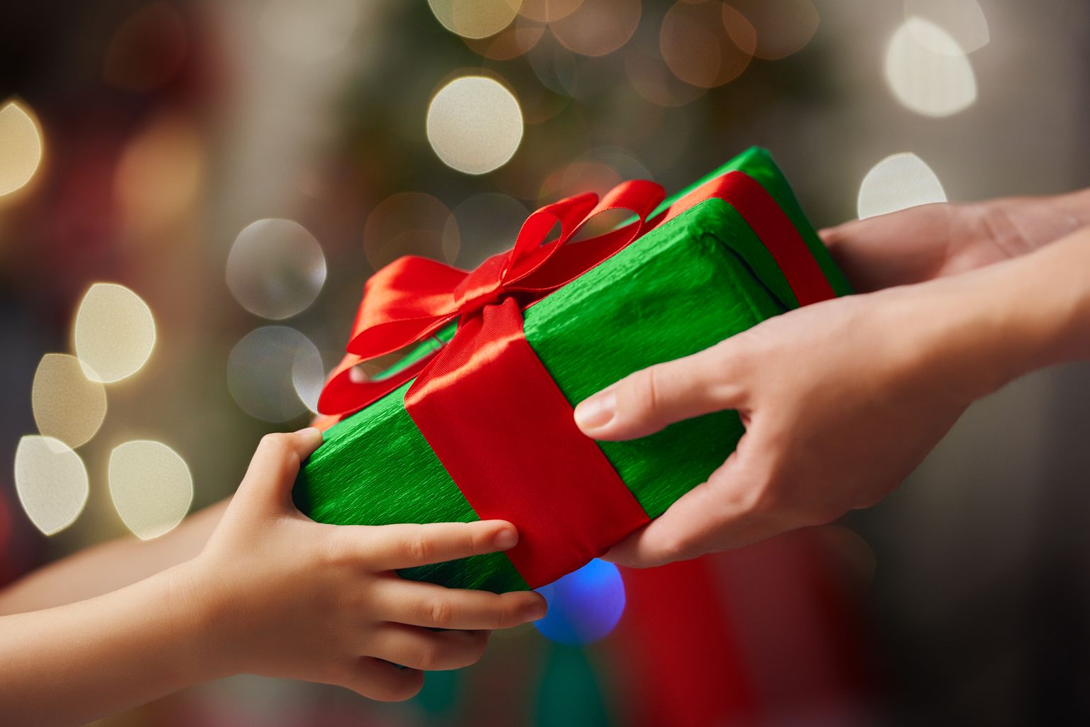 Hands of parent giving a Christmas gift to child.