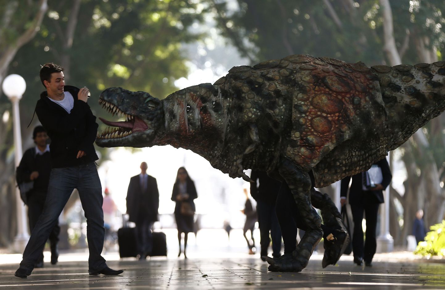 A man reacts as a performer dressed in a Tyrannosaurus rex dinosaur costume walks next to him during a publicity event in central Sydney August 28, 2013. The performance was a promotion for an upcoming exhibition at the Australian Museum titled "Tyrannosaurs - Meet the Family" which showcases ancestors of the Tyrannosaurus rex, with more than 10 life-size dinosaur specimens on display.   REUTERS/Daniel Munoz   (AUSTRALIA - Tags: SOCIETY TPX IMAGES OF THE DAY)