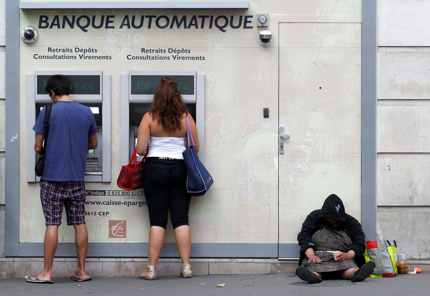 Kodutu naine Pariisis pangaautomaadi kõrval.