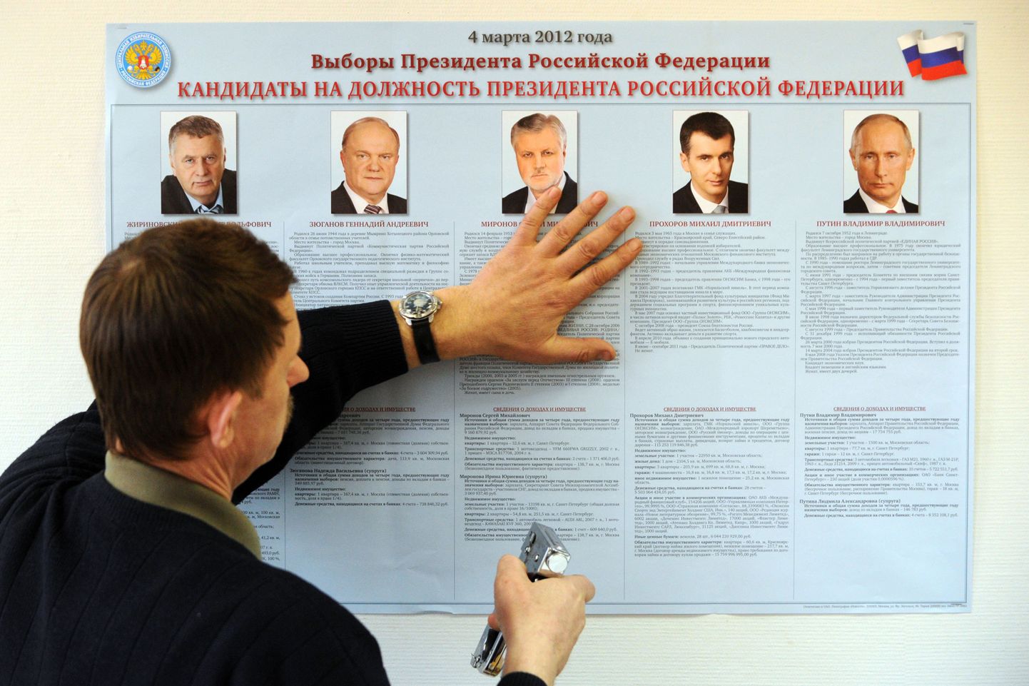 Keskvalimiskomisjoni töötaja kinnitab viie presidendikandidaadi tutvustust jaoskonna seinale Moskvas.