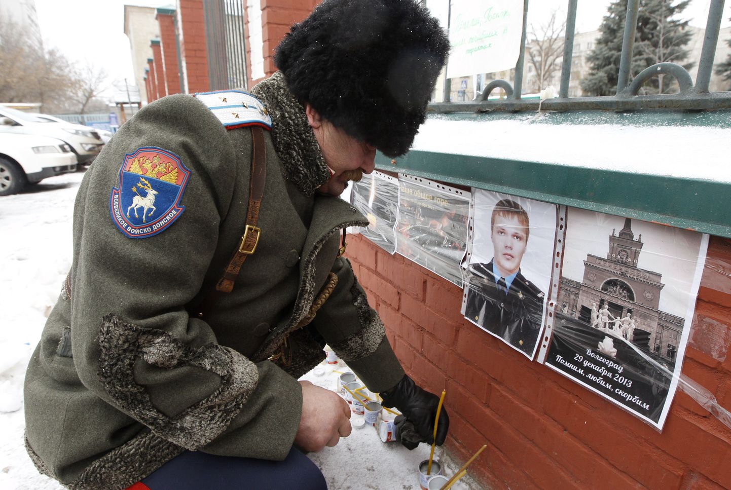 Казак ставит свечку рядом с фотографией Дмитрия Маковкина.