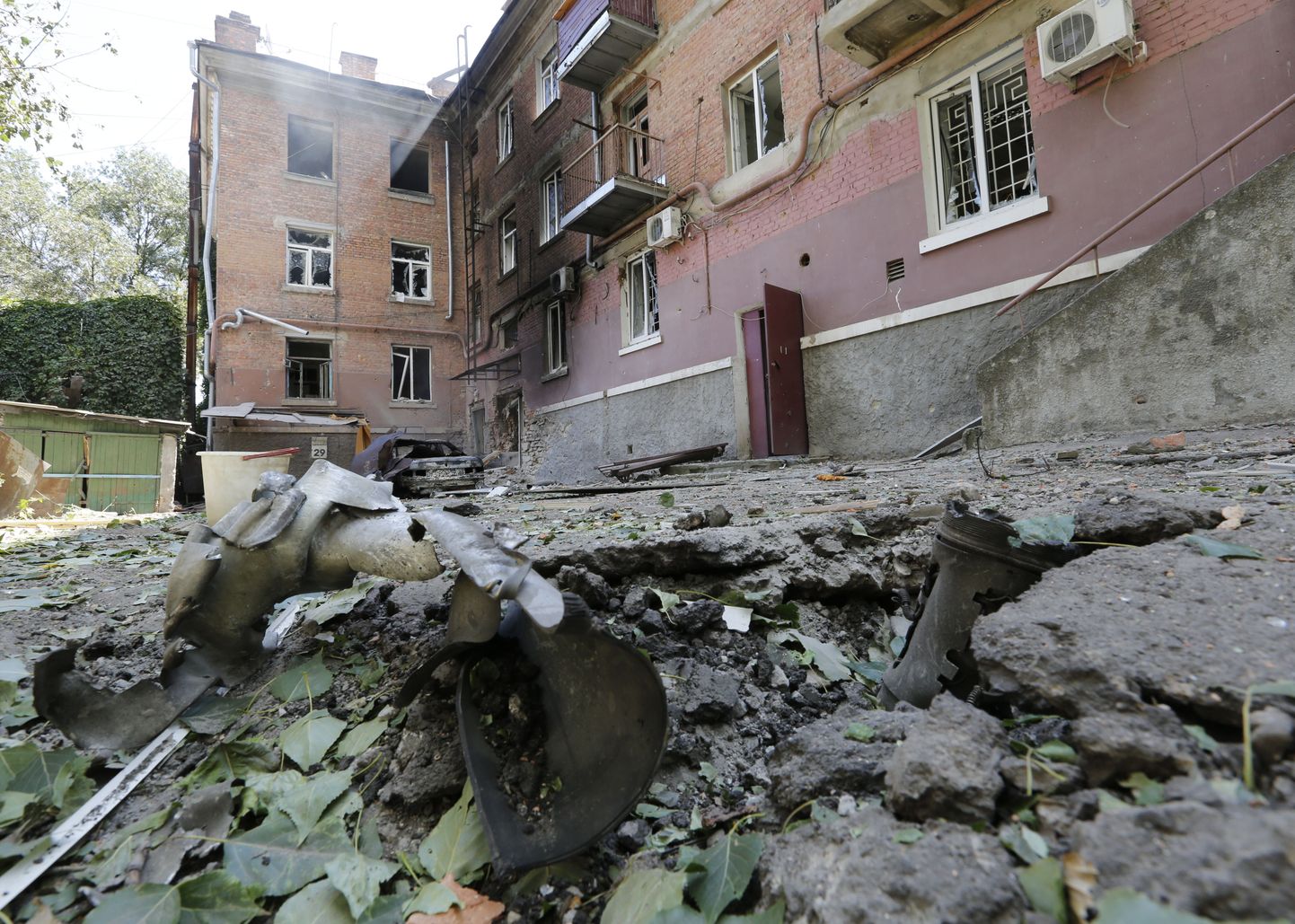 Воронка от разрыва снаряда рядом с жилым домом в Луганске.