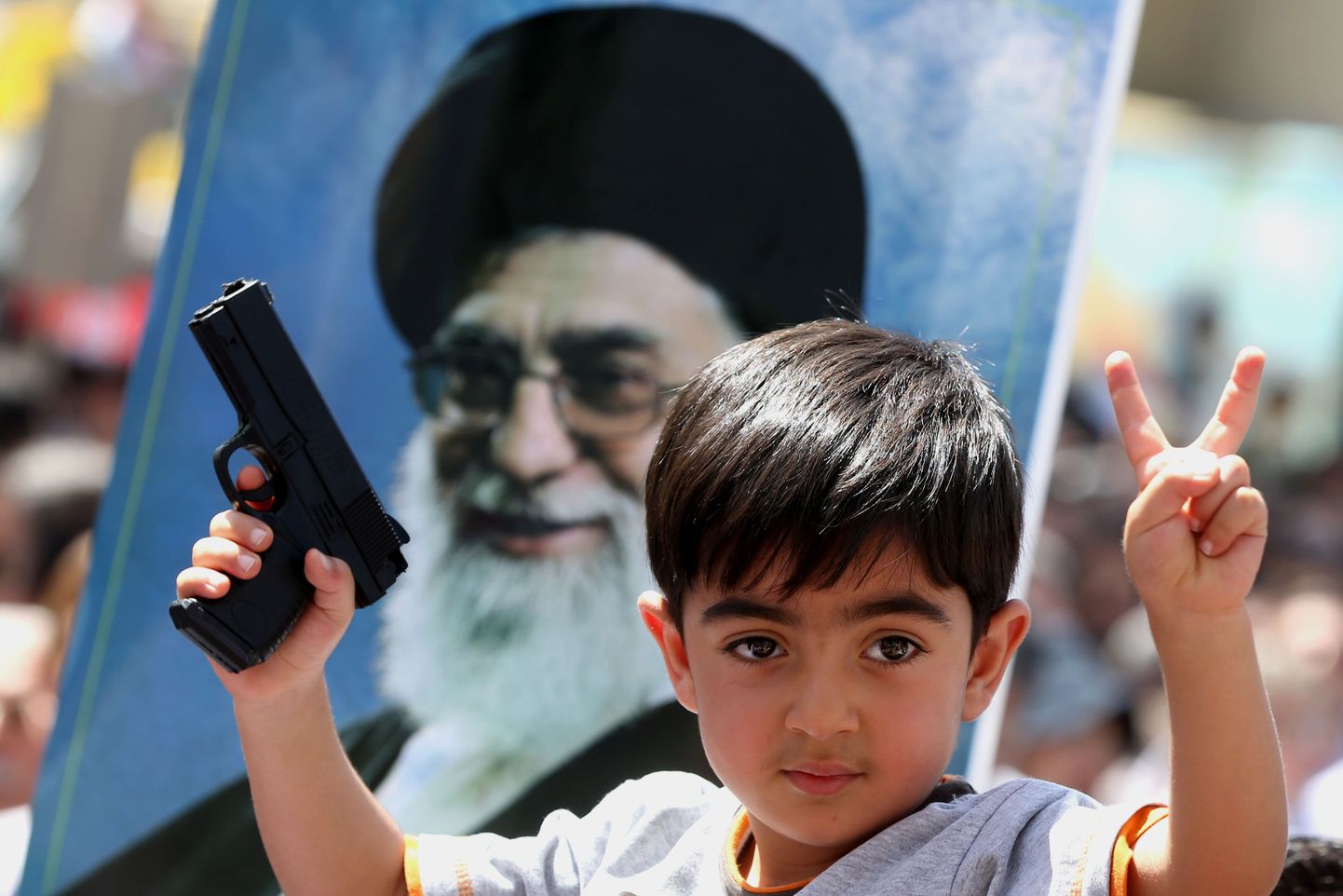 Väike Iraanis elav iraagi poiss ajatolla Khamenei pildi taustal.