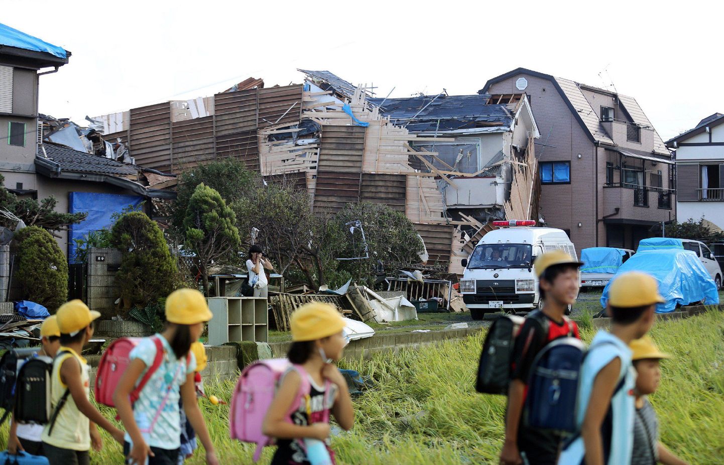 Koshigaya linna koolilapsed eile möödumas tornaado purustatud majast.