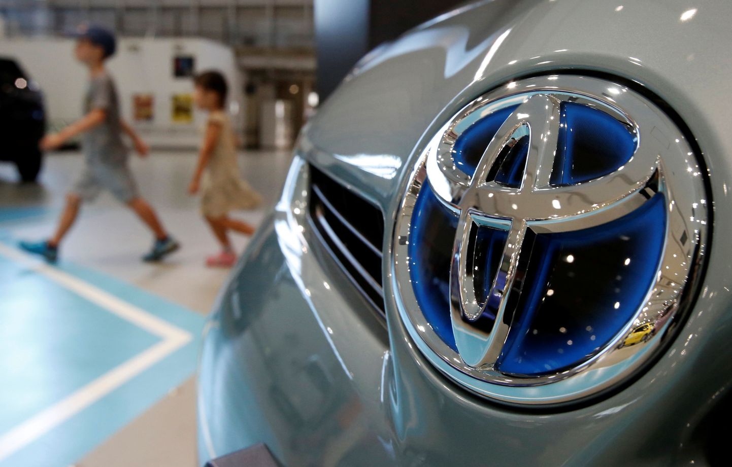 Visitors walk past a logo of Toyota Motor Corp on a Toyota Prius hybrid vehicle at the company's showroom in Tokyo August 5, 2014.   REUTERS/Yuya Shino/File Photo