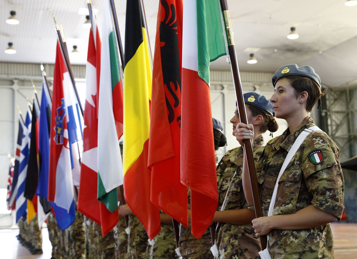 Солдаты с флагами стран НАТО в руках на церемонии открытия военных маневров в Италии 19 октября.