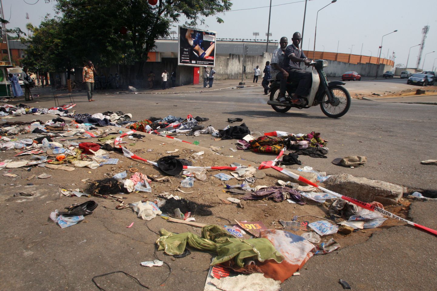 Mootorratas möödub Abidjani tänaval lebavatest riietest ja muudest esemetest. Samas tallati öösel surnuks ligi 60 inimest.