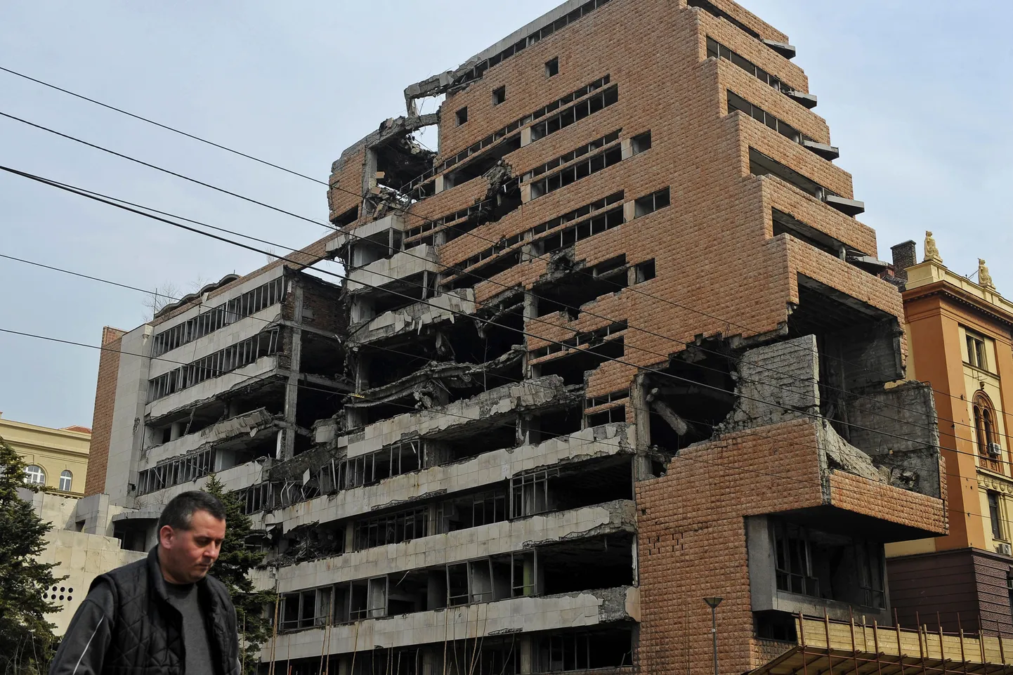 Мужчина идет мимо здания в Белграде, разрушенного в результате авиаударов самолетов НАТО.