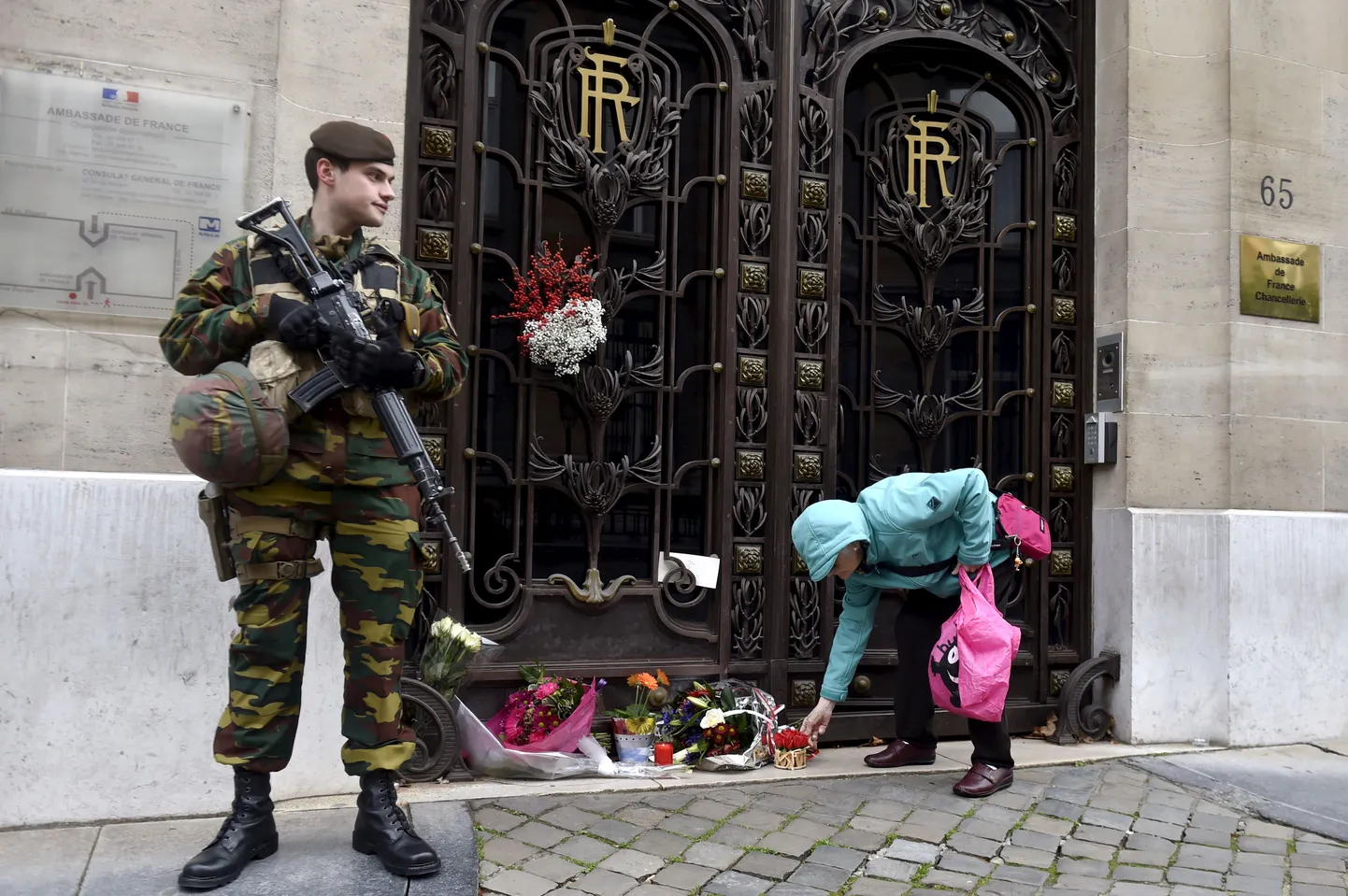 Belgia sõdur vaatamas, kuidas naine paneb lilli Prantsuse saatkonna juurde Brüsselis.