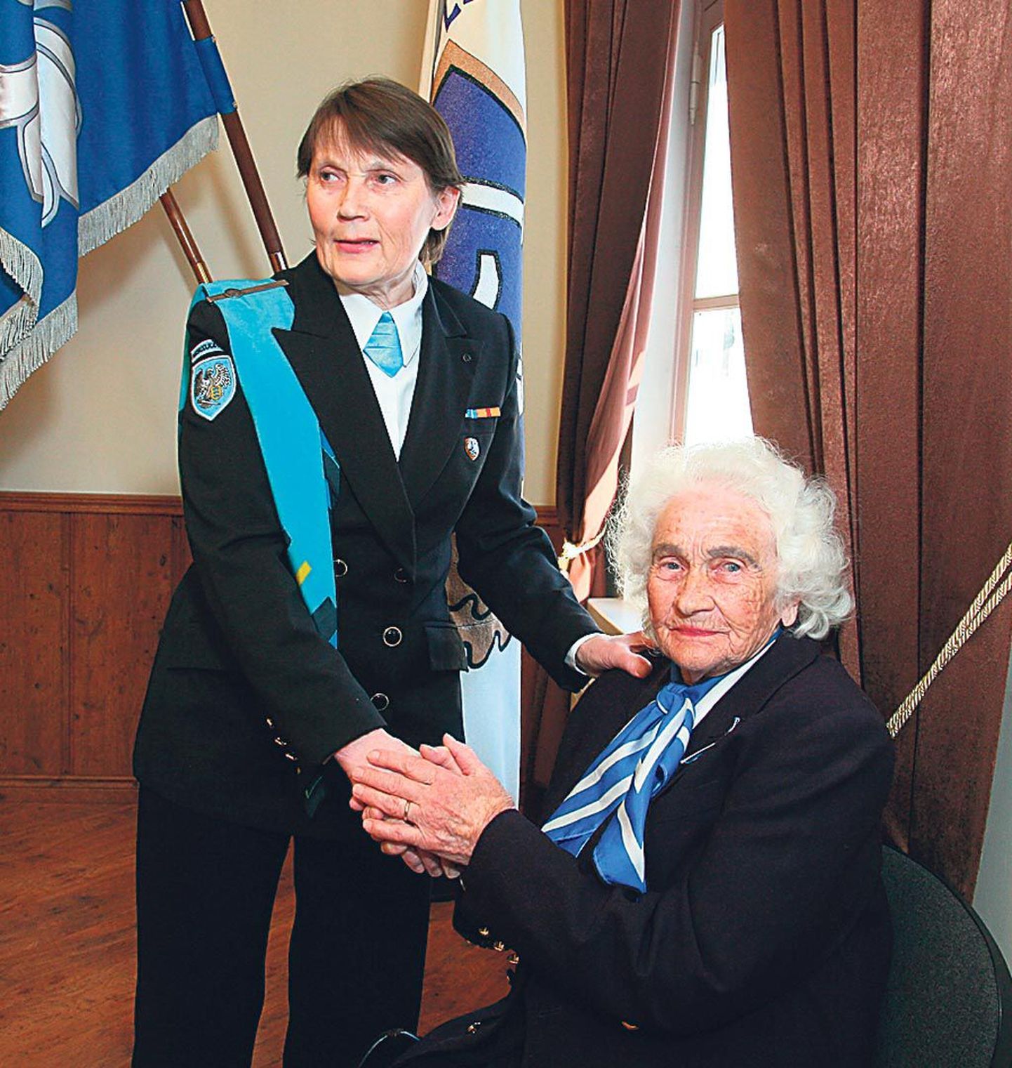 Naiskodukaitse Pärnumaa ringkonna lipu taustal jutlevad ringkonna esinaine Maie Pitsal (vasakul) ja auliige Elfriede Laidvee, liige 1936. aastast.