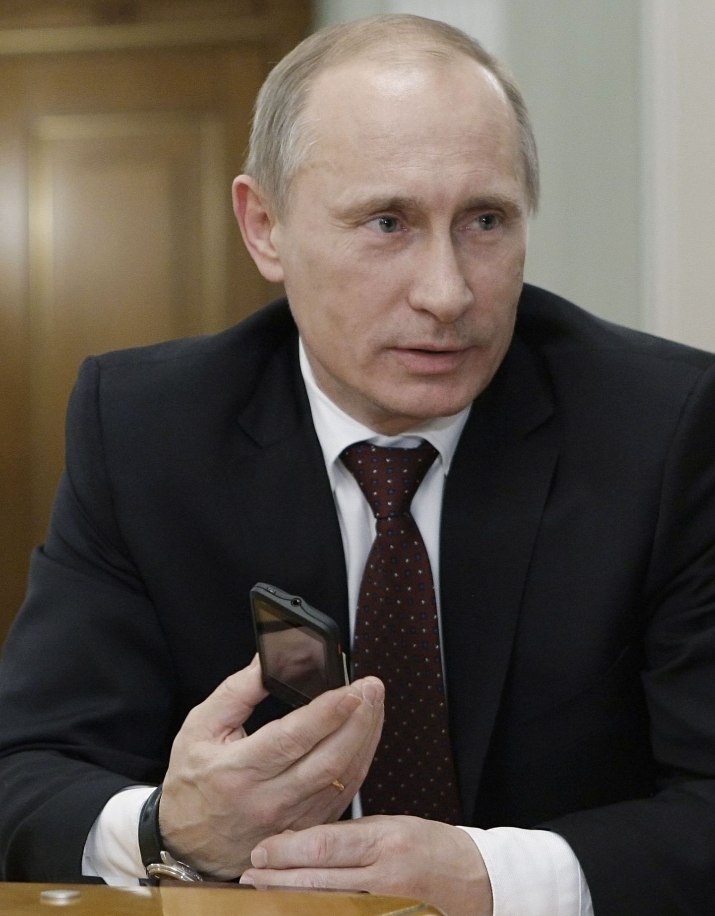 Премьер-министр РФ Владимир Путин держит в руках новый российский мобильный телефон.