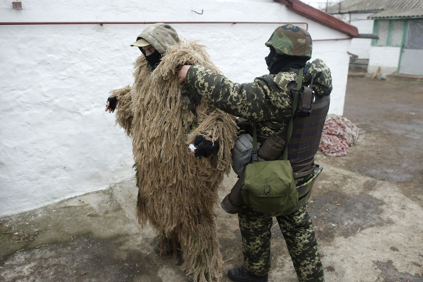 Ukraina sõdurd aitab kamuflaaži kandvat kaaslast Mariupoli lähistel.
