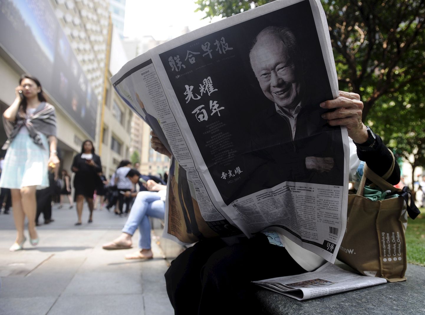Женщина читает газету с сообщением о смерти Ли Куан Ю.