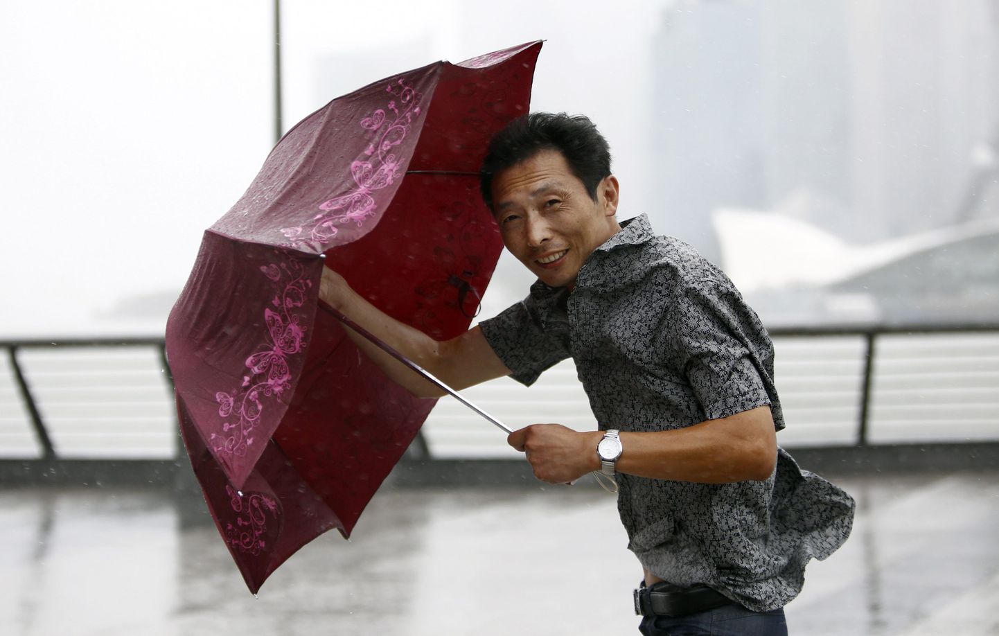 Taifuun Muifast pääsenud Shanghai elanik kiivalt vihmavarjust kinni hoidmas.