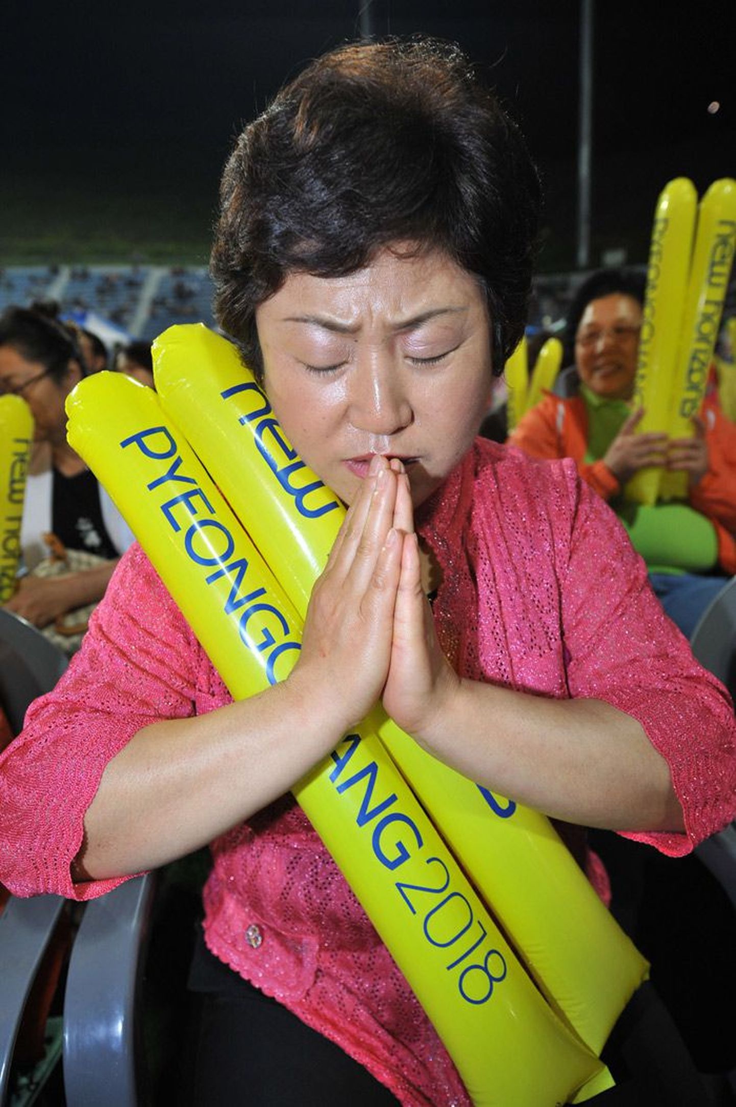 Кореянка, следившая на большом экране за выборами места проведения зимней Олимпиады 2018 года, возносит благодарственную молитву.
