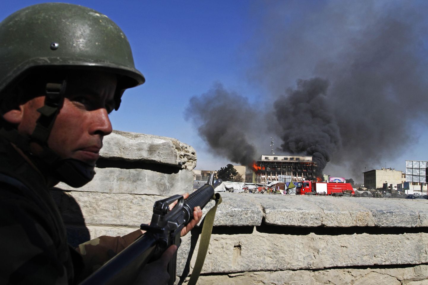 AFganistani politseinik Kabuli põleva hoone taustal vahti pidamas.