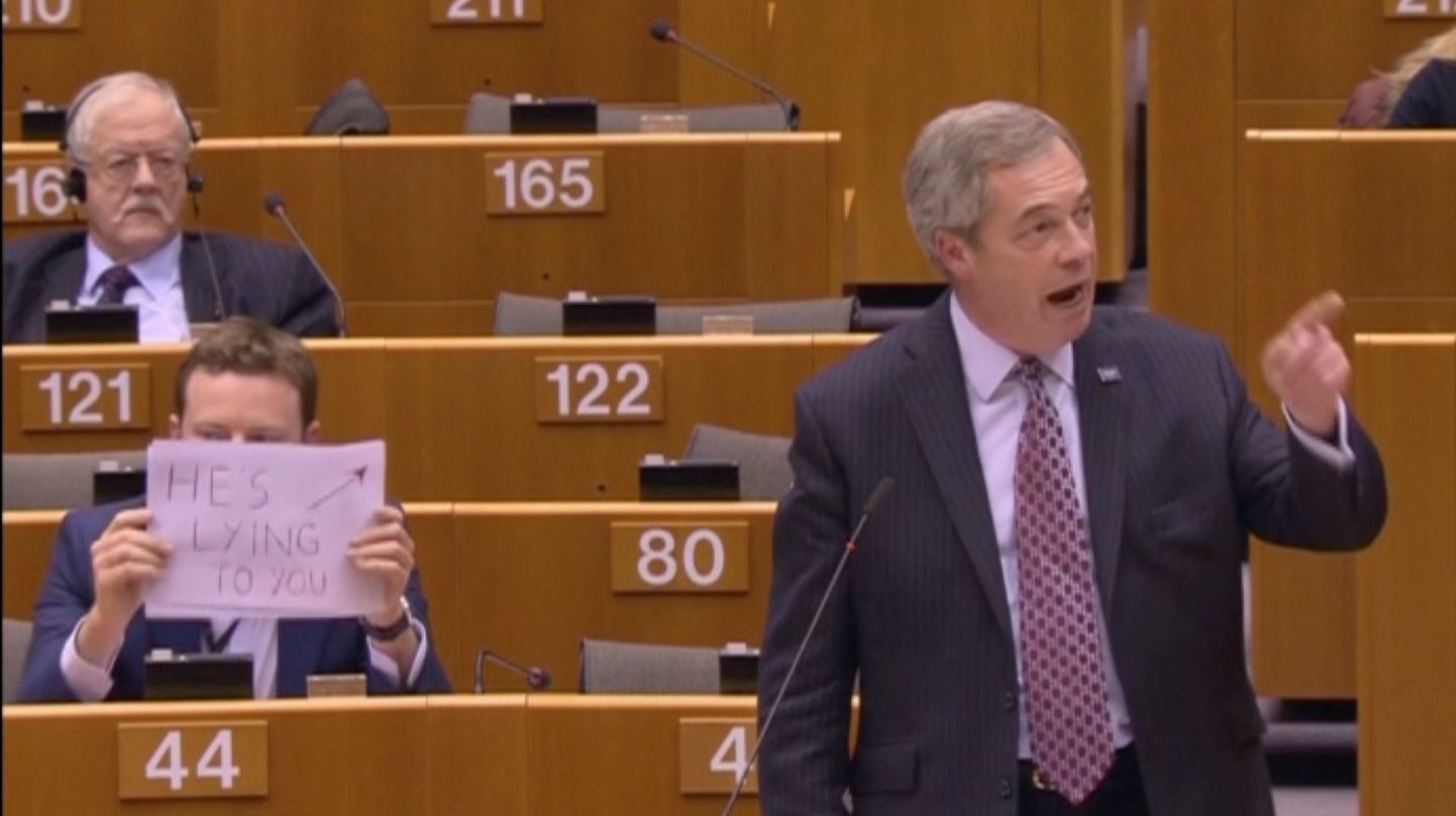 Nigel Farage eile kõnet pidamas, selja taga plakatit hoidev Seb Dance.