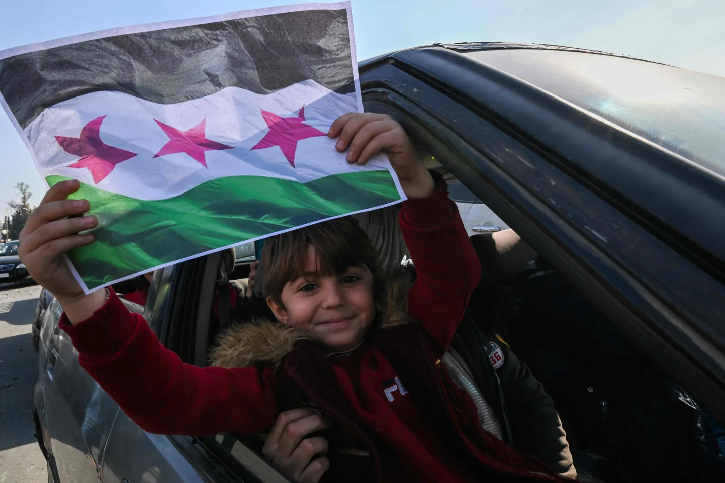 Laps 9. detsembril 2024 Damaskuses Süüria opositsiooni lipuga. Süüria mässulised kukutasid diktaatorist presidendi Bashar al-Assadi režiimi. Al-Assad põgenes koos perekonna ja lähikondlastega Venemaale Moskvasse, kus sai Vene võimude teatel humanitaarkaalutlustel asüüli