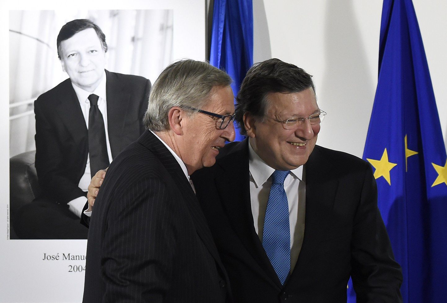 Outgoing EU Commission head Jose Manuel Barroso (R) embraces EU president-elect Jean-Claude Juncker at the EU headquarters in Brussels on October 30, 2014 after unveiling a portrait of Barroso to be exhibited in the Presidential Gallery of the Berlaymont building as part of a symbolic gesture in the handover of the EU Commission presidency. AFP PHOTO/JOHN THYS