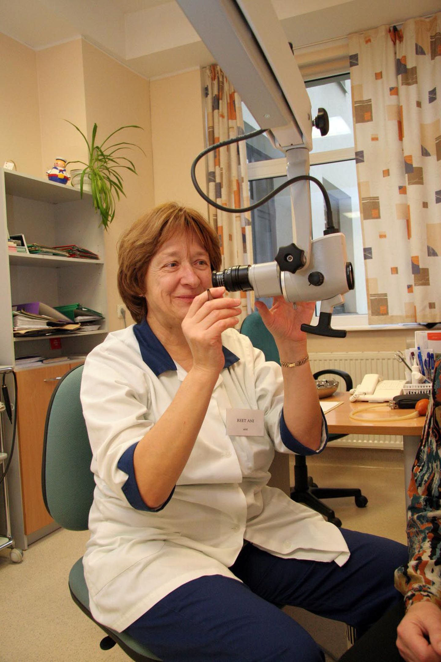 Kõrva-nina-kurguarst Reet Ani hakkab kõrvamikroskoobiga patsiendi kõrva uurima.