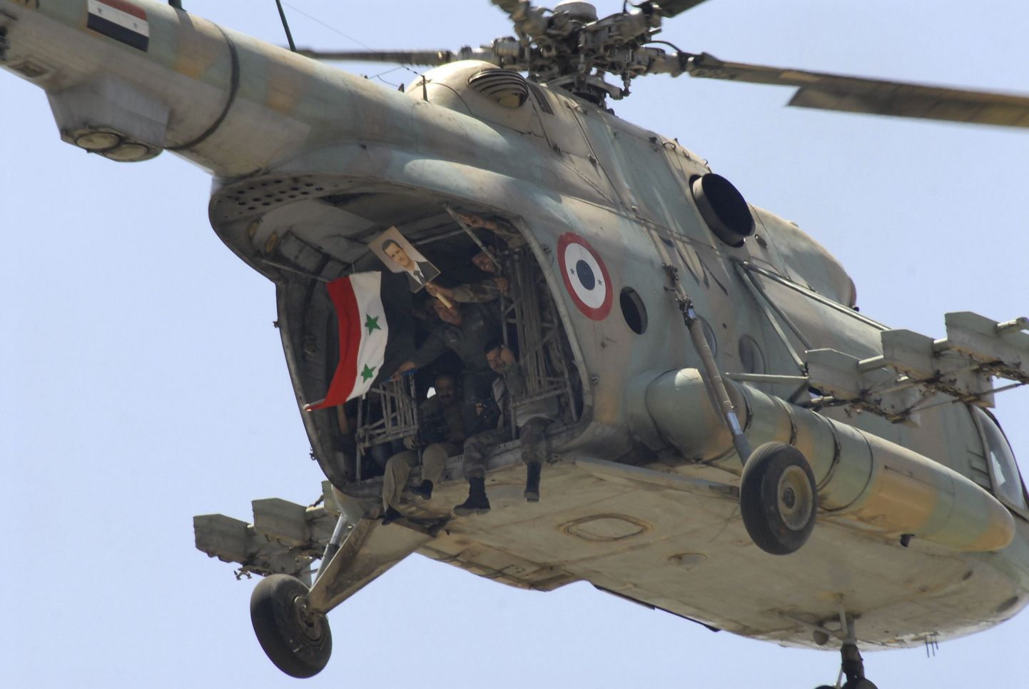 Süüria sõdurid helikopteris lehvitamas Süüria lipu ja presidendi pildiga.
