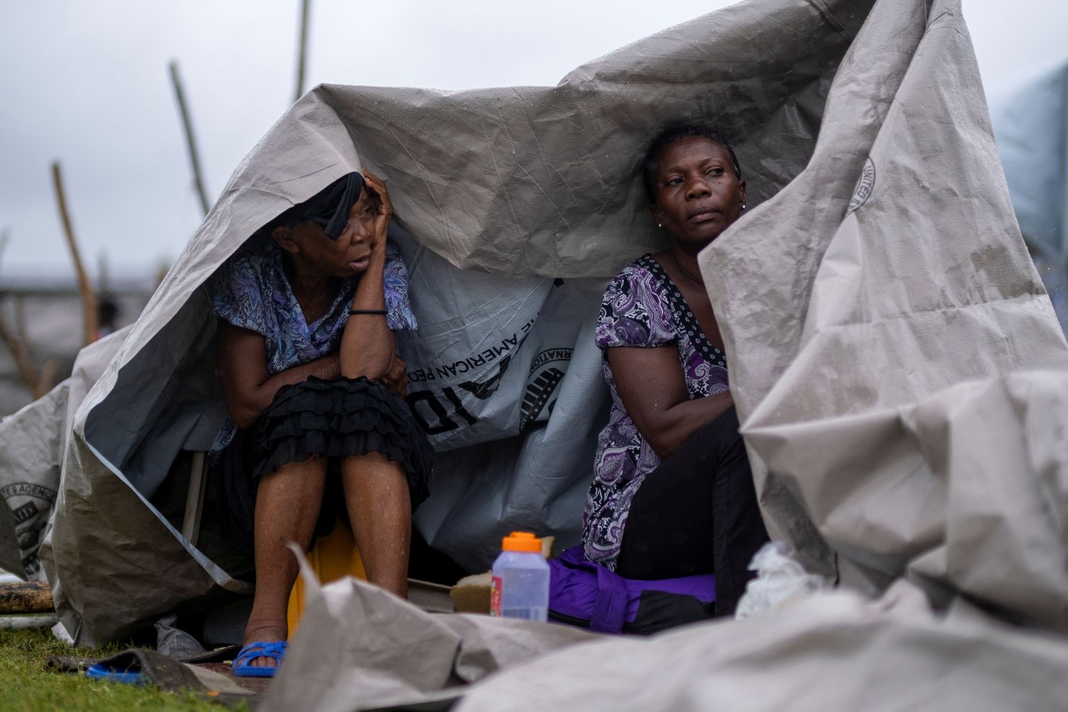 Kaks naist otsivad varju vihma eest Les Cayes’ linnas maavärinaohvrite ajutises laagris.