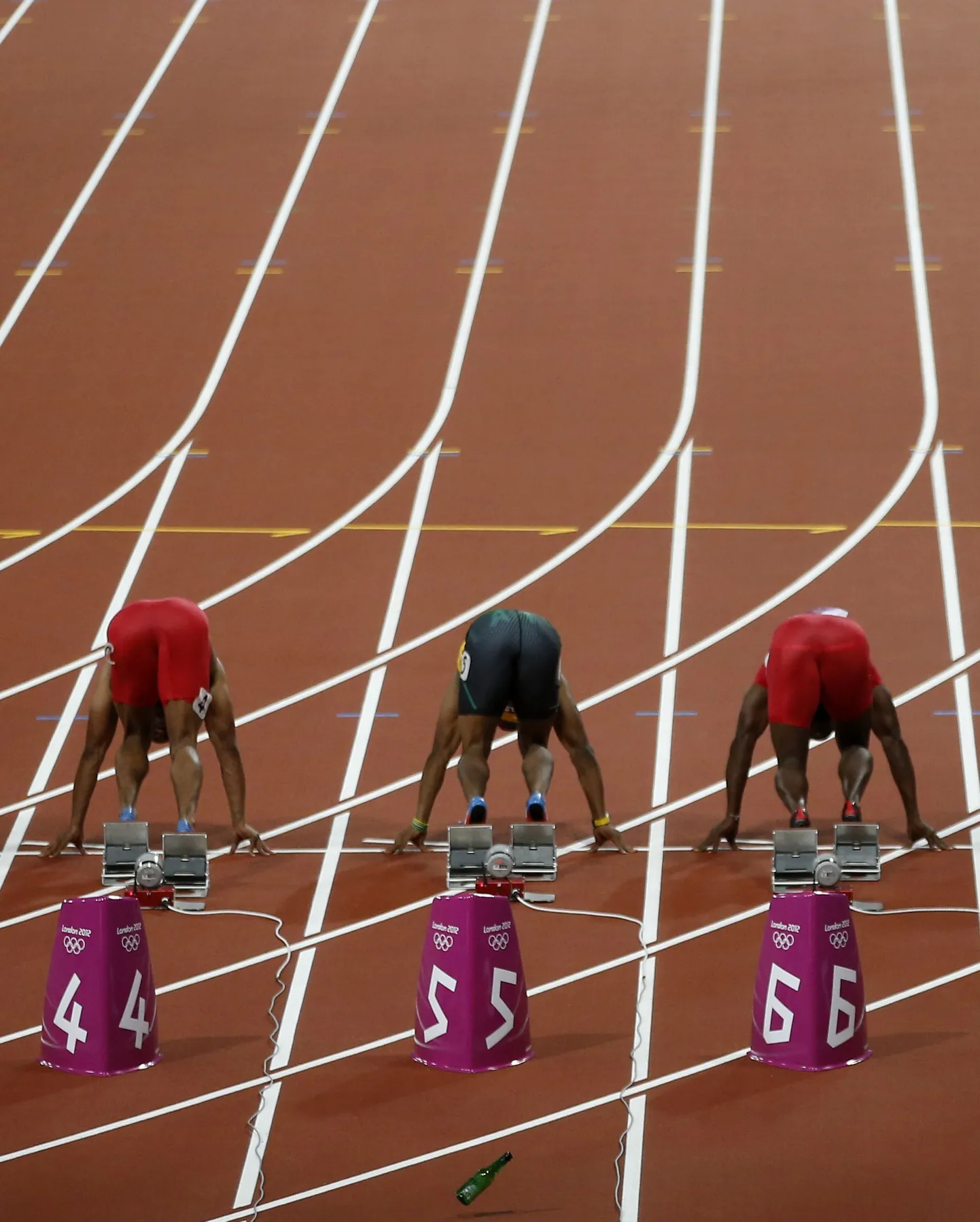 Meeste 100 meetri jooksu start olümpial. Esiplaanil on näha rajale visatud õllepudel.