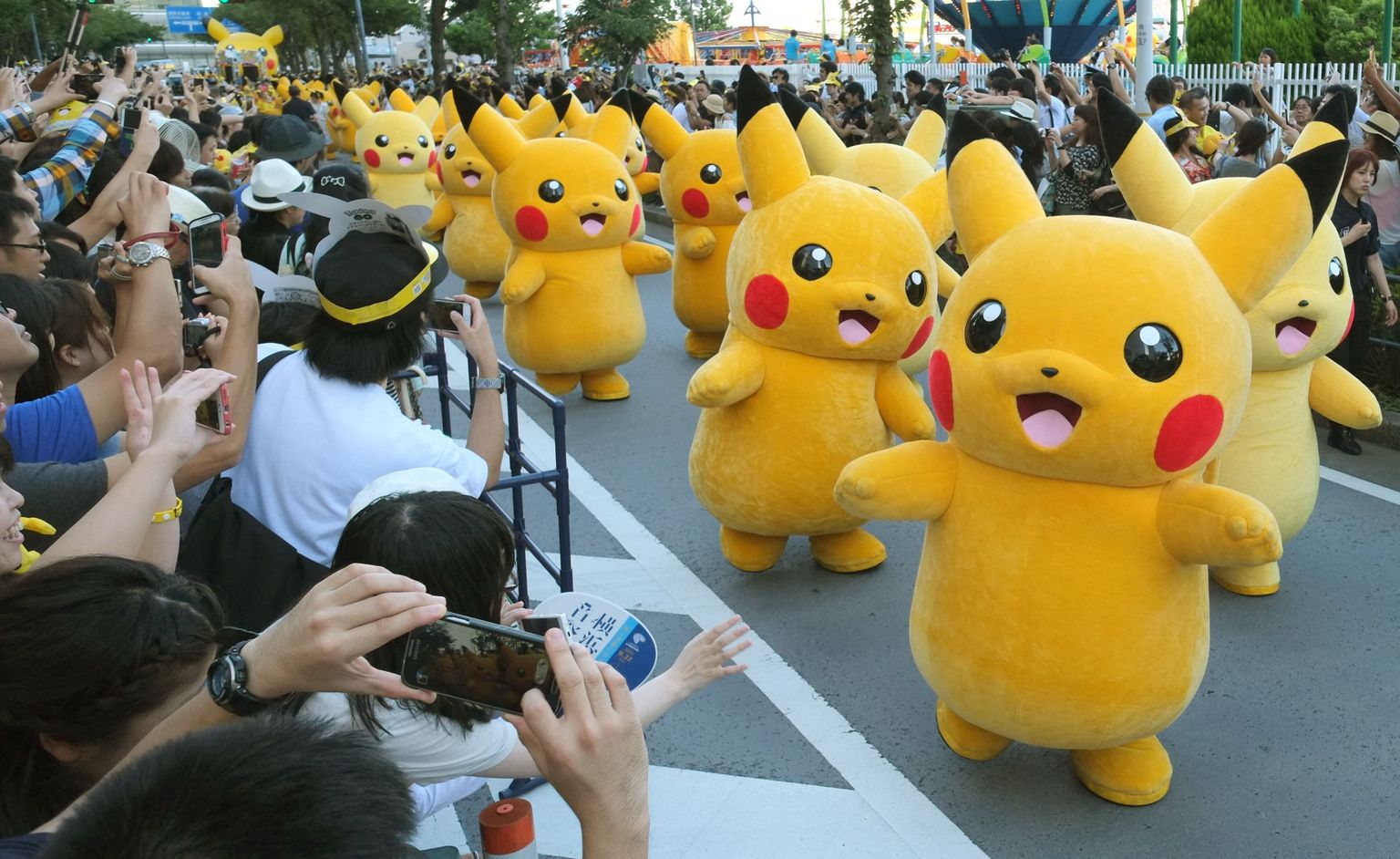 Performers dressed as Pikachu, the popular animation Pokemon series character, perform in the Pikachu parade in Yokohama on August 7, 2016. 
Some 50 life-size Pikachu characters, the most famous from the Pokemon game, marched along the city's waterfront street as visitors took mobile phone pictures and videos of them in scorching sunshine. / AFP PHOTO / KAZUHIRO NOGI