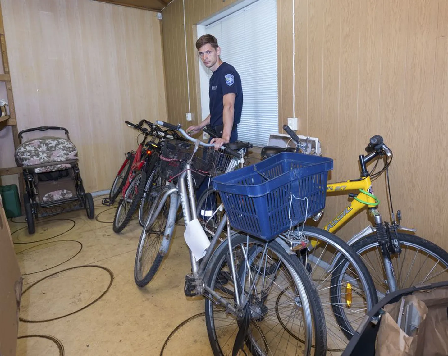 Politseinik Hegert Heil näitab lapsevankrit ja kuut jalgratast, mis ootavad koos omanikke.