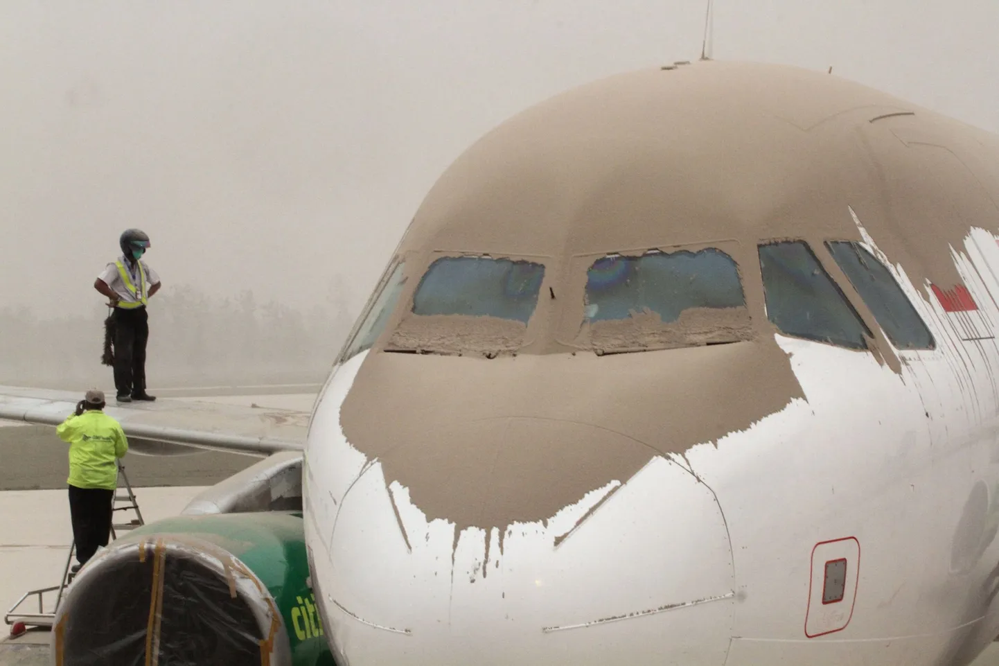 Indonesian airport personnel inspect volcanic ash covered planes and the airport of Yogyakarta about 200 kilometers (124 miles) west of the Mount Kelud volcano in East Java province following its eruption on February 14, 2014. A spectacular volcanic eruption in Indonesia has killed at least two people and forced mass evacuations, disrupting long-haul flights and closing international airports Friday.  AFP PHOTO / NINOY