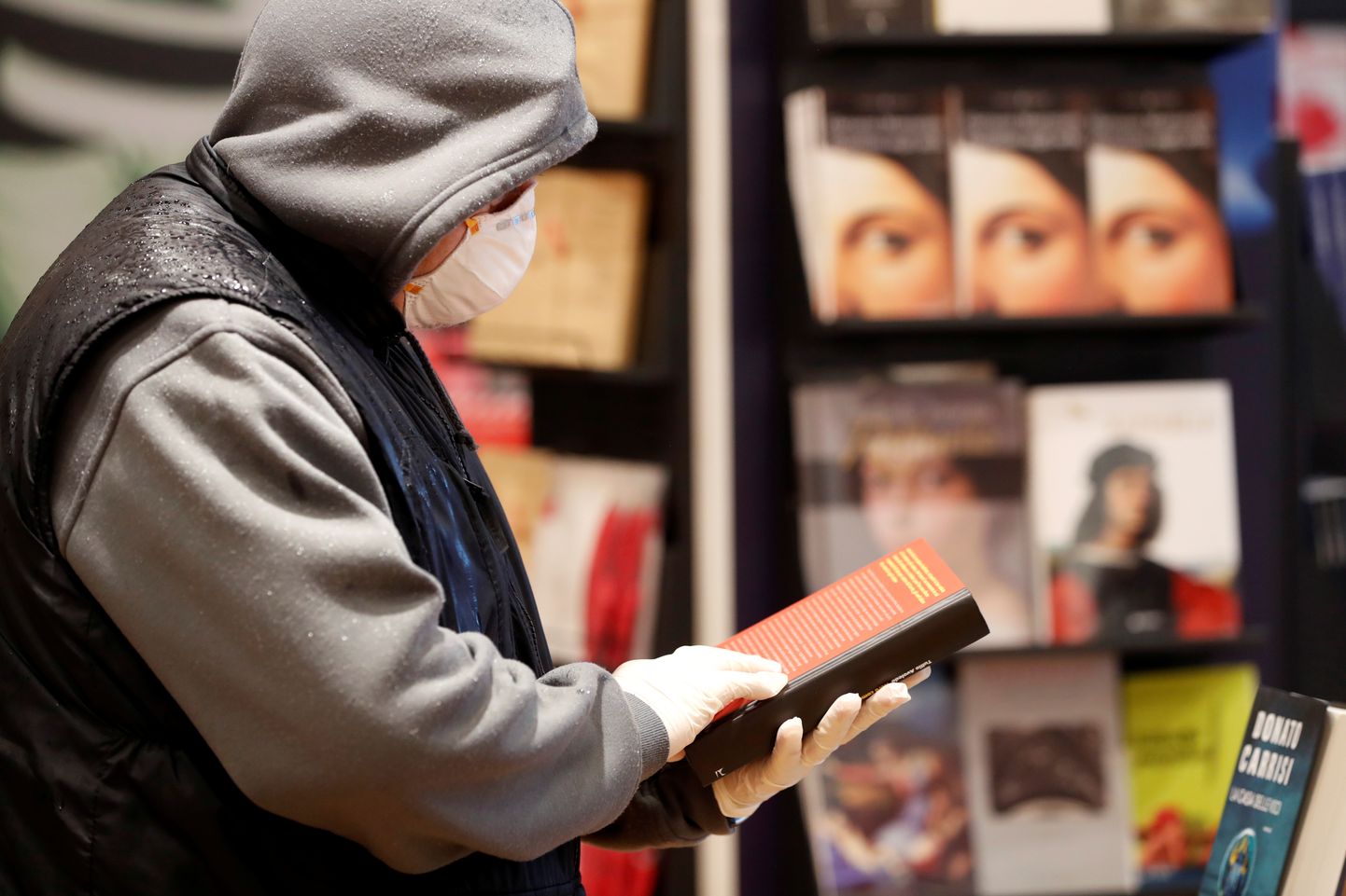 Kaitsemaski ja kindaid kandev lugeja ühes taasavatud raamatupoes Roomas.