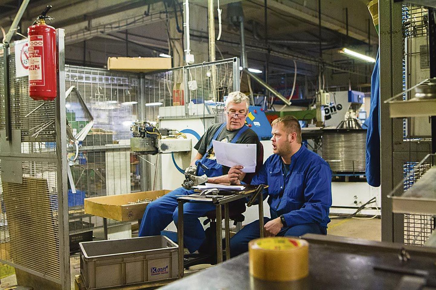 Tootmishoones peavad töötajad joonise üle aru 3D-traadipainutuspingi juures.