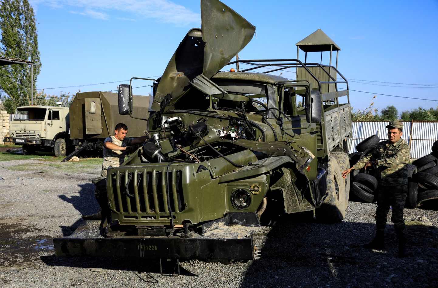 Armēņu karavīri apskata bojātu transportlīdzekli.