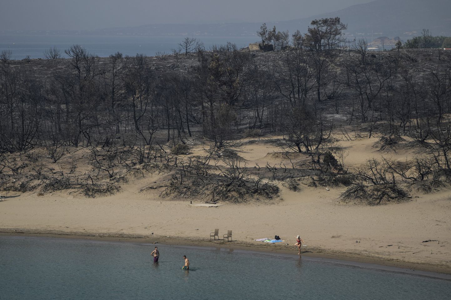 Люди купаются у берегов острова Родос (Греция) после ландшафтного пожара.