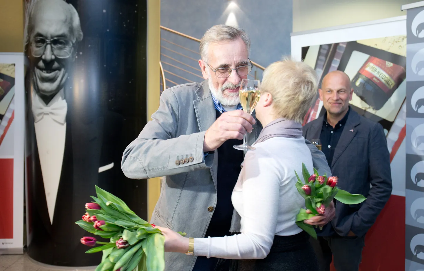 Näitleja Lembit Ulfsak on äsja saanud tulbikimbu Eesti Filmi Instituudi peaprodutsendilt Piret Tibbo-Hudginsilt. tagaplaanil «Mandariinide» produtsent Ivo Felt.