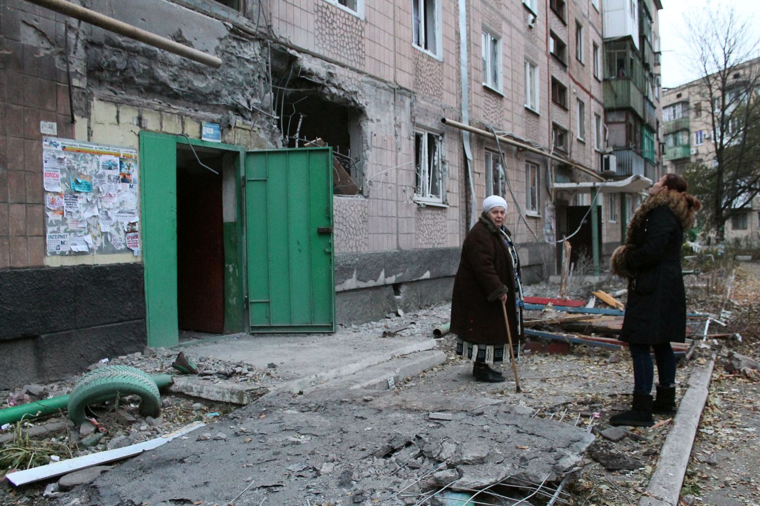 Kohalikud mürsutules kahjustada saanud Makejevka korterelamu ees.