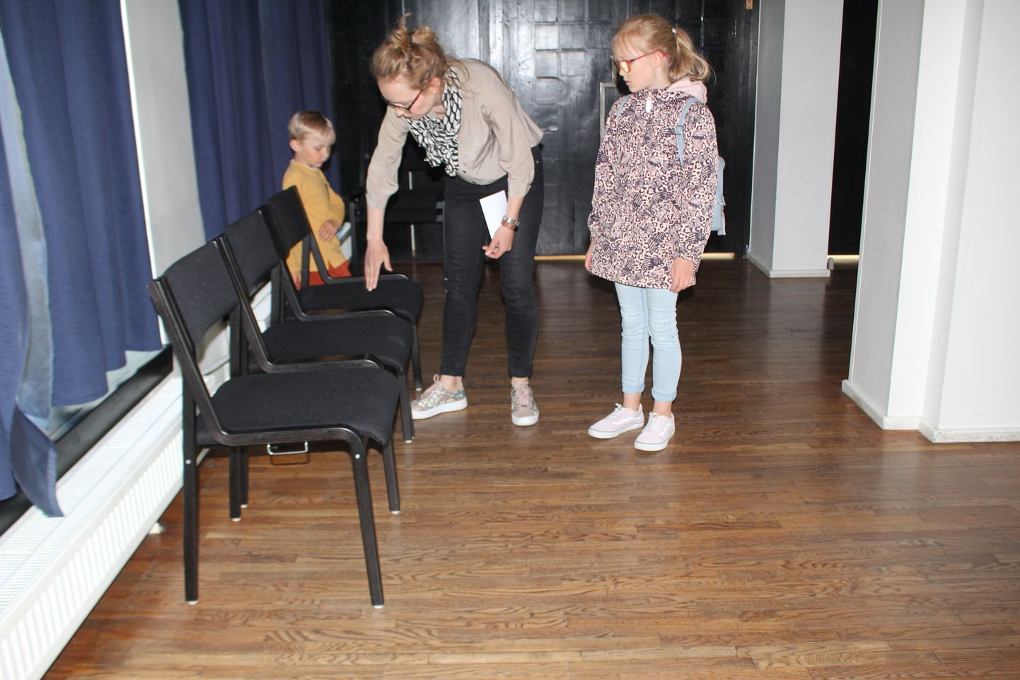 Paide muusika- ja teatrimaja direktor Martha-Beryl Grauberg näitab, kuidas uued toolid saab üksteise külge ritta kinnitada.