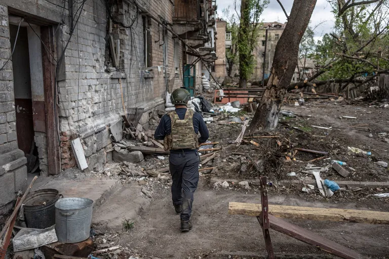 Украинский волонтер идет среди разрушенных домов в Часовом Яру.