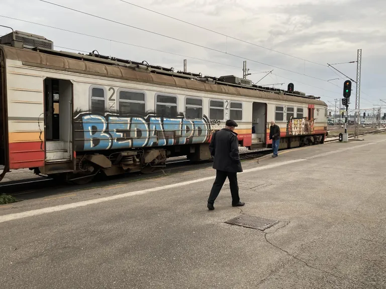 Grafitiga rong on lennuvälja lähistelt odavaim tee Podgoricasse. Vahepeal käib ainsat rongiootajat oma autosse rääkimas ka taksojuht, kes langetab lõpuks sõidu hinnapakkumise suisa kaheksale eurole.